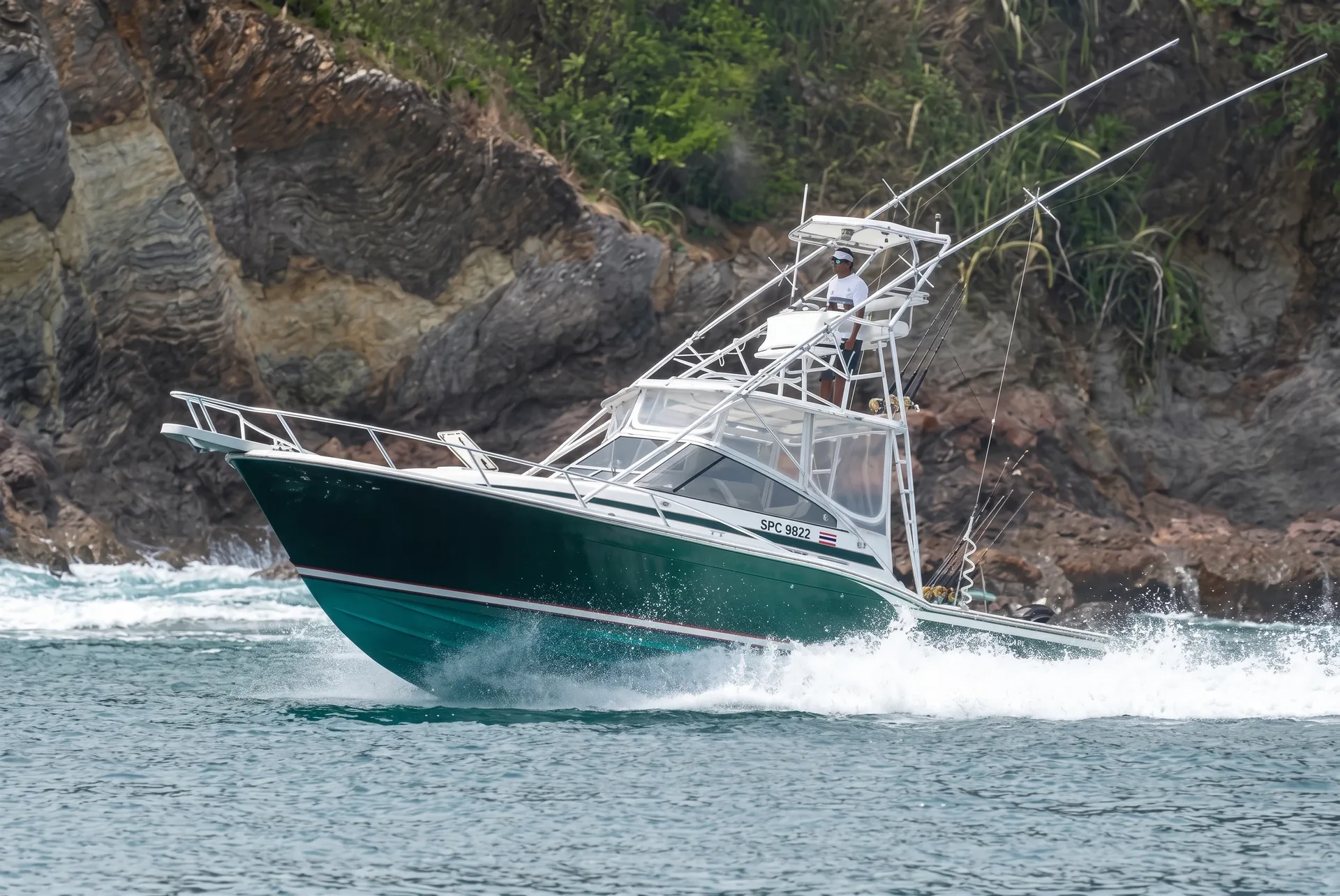 Runaway, a green-hulled sport fishing Boat, running at speed past a rocky shore