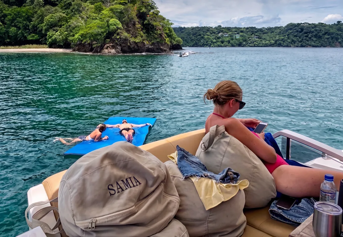 Guests relaxing on a floating mat off the back of a luxury charter, secluded cove near Papagayo