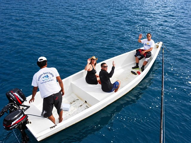 Guests wave from the dinghy that ferries them out to the Boat, seen from the Boat's deck