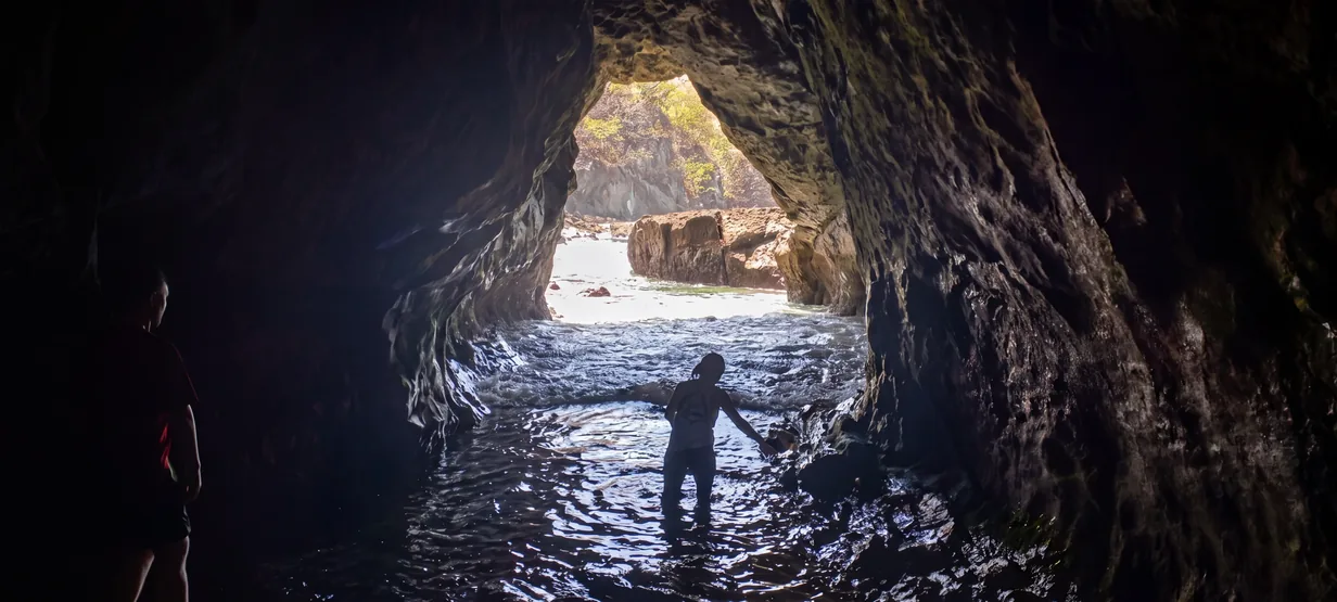 Two visitors wading through a sea cave on a Gulf of Papagayo beach day tour
