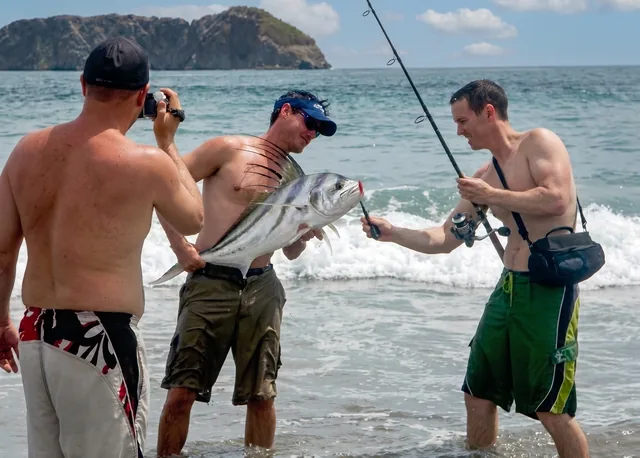 Anglers with a roosterfish caught from shore, rocky coastline near Papagayo